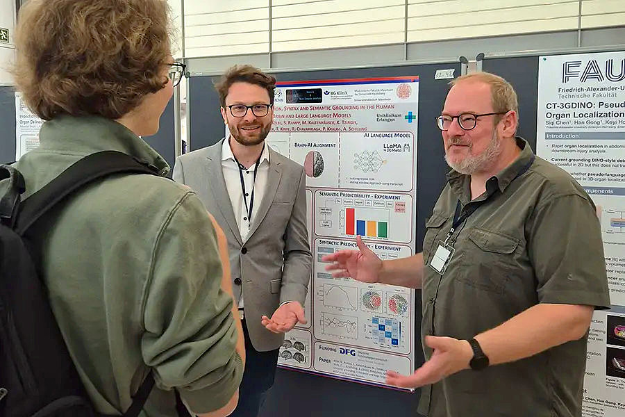 2 Wissenschaftler im Gespräch mit einem Studenten vor einer Posterwand