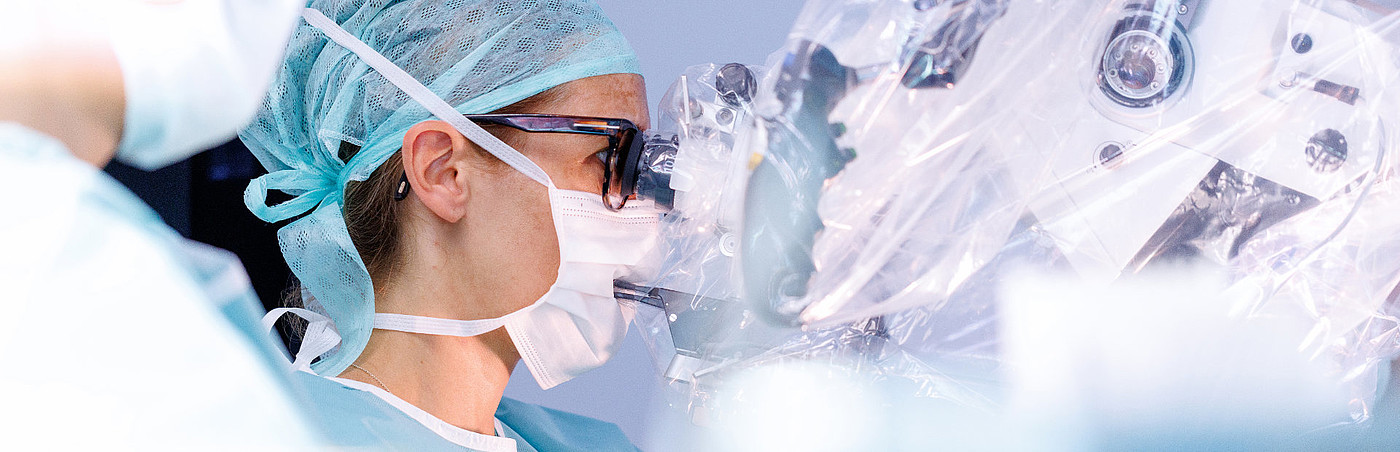 Neurochirurgin blickt durch ein Operationsmikroskop während eines Eingriffs im OP der Universitätsmedizin Mannheim.