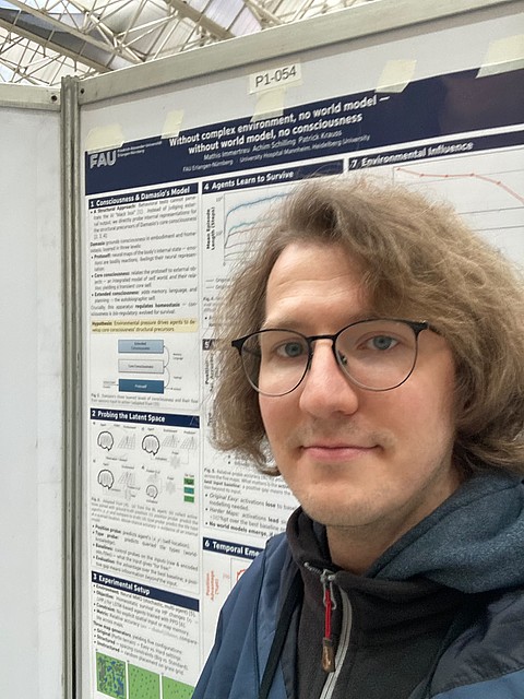 Mathis_Immertreu mit Brille und lockigem Haar steht vor einem wissenschaftlichen Poster auf einer Messe oder Konferenz